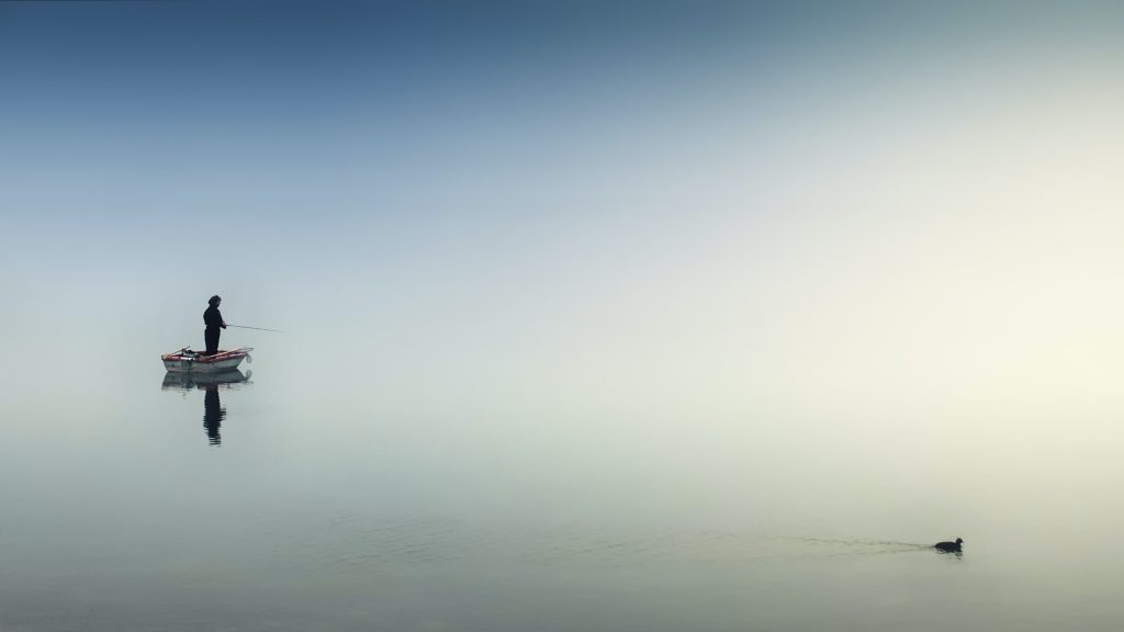 Person on White Boat Fishing on Body of Water